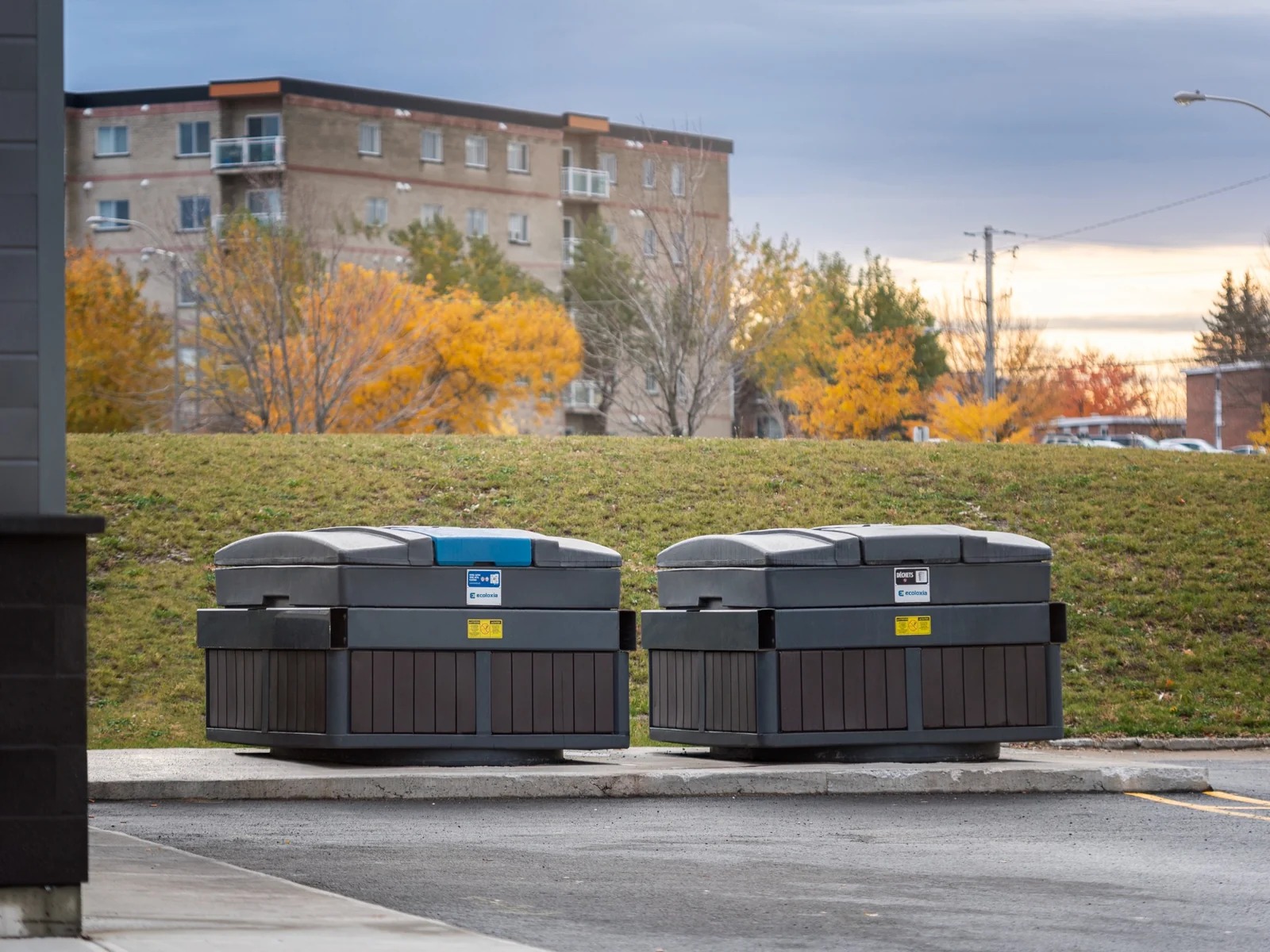 Deux conteneurs CUBE semi-enfouis 6,5 v Ecoloxia avec panneaux noyer installes pour un projet commercial a La Prairie, Quebec